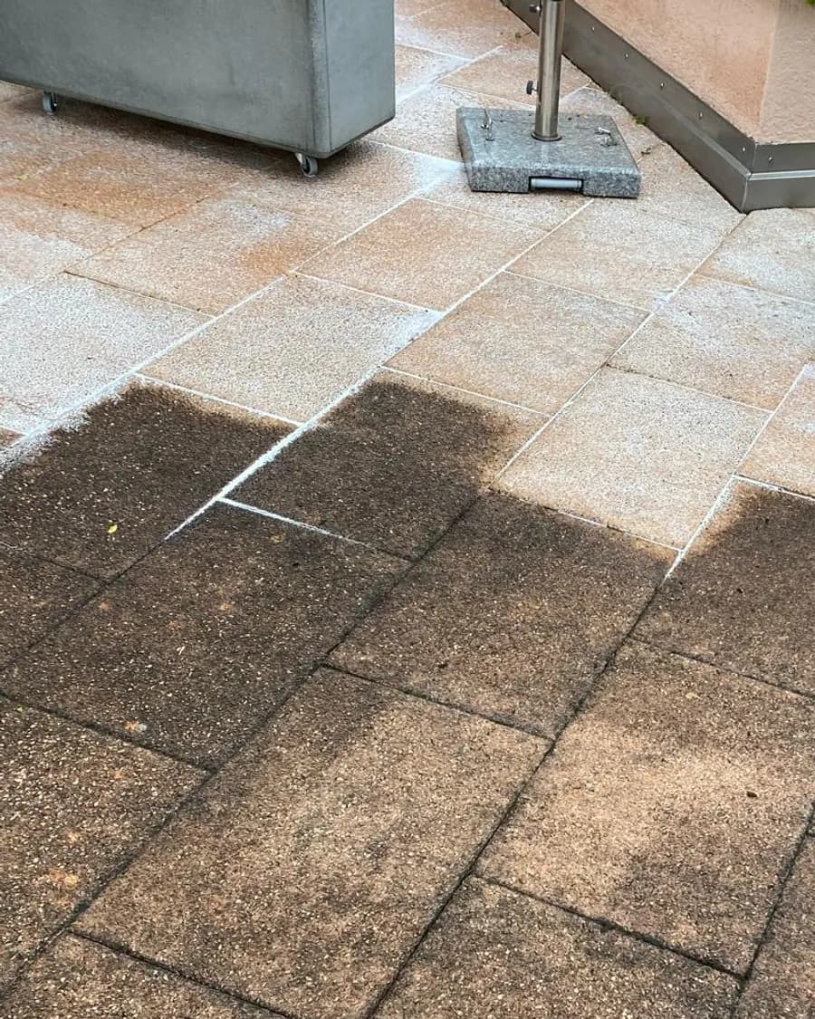 Terrassenplatten, oben gereinigt und hell, unten noch dunkel verschmutzt, daneben Pflanzkübel aus Beton