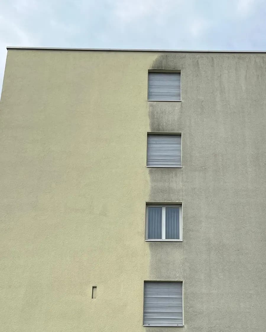 Verputzte Hausfassade, links gereinigt und hell, rechts noch mit grauen Schmutzfahnen